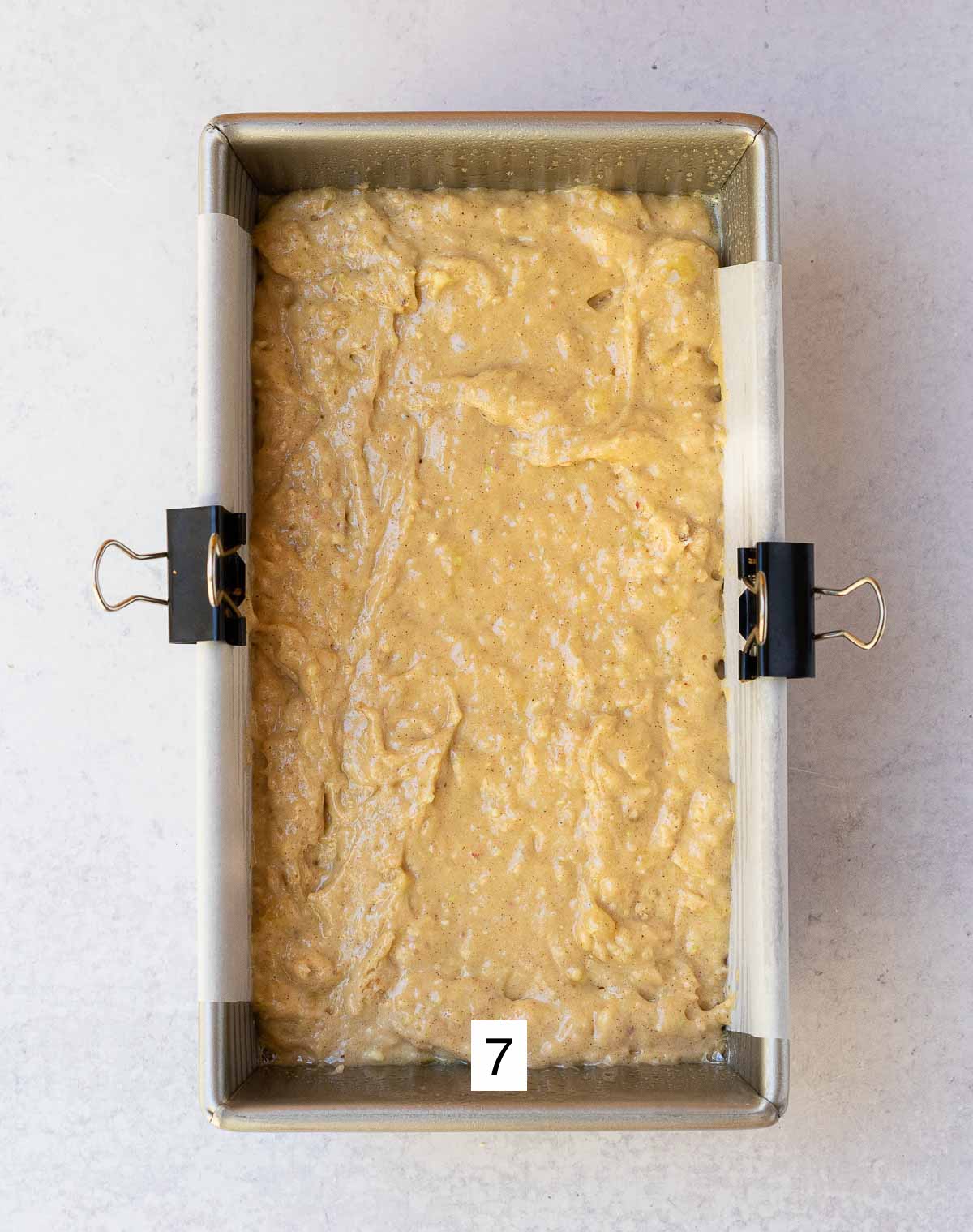 banana apple bread mixture placed in loaf pan lined with parchment paper.