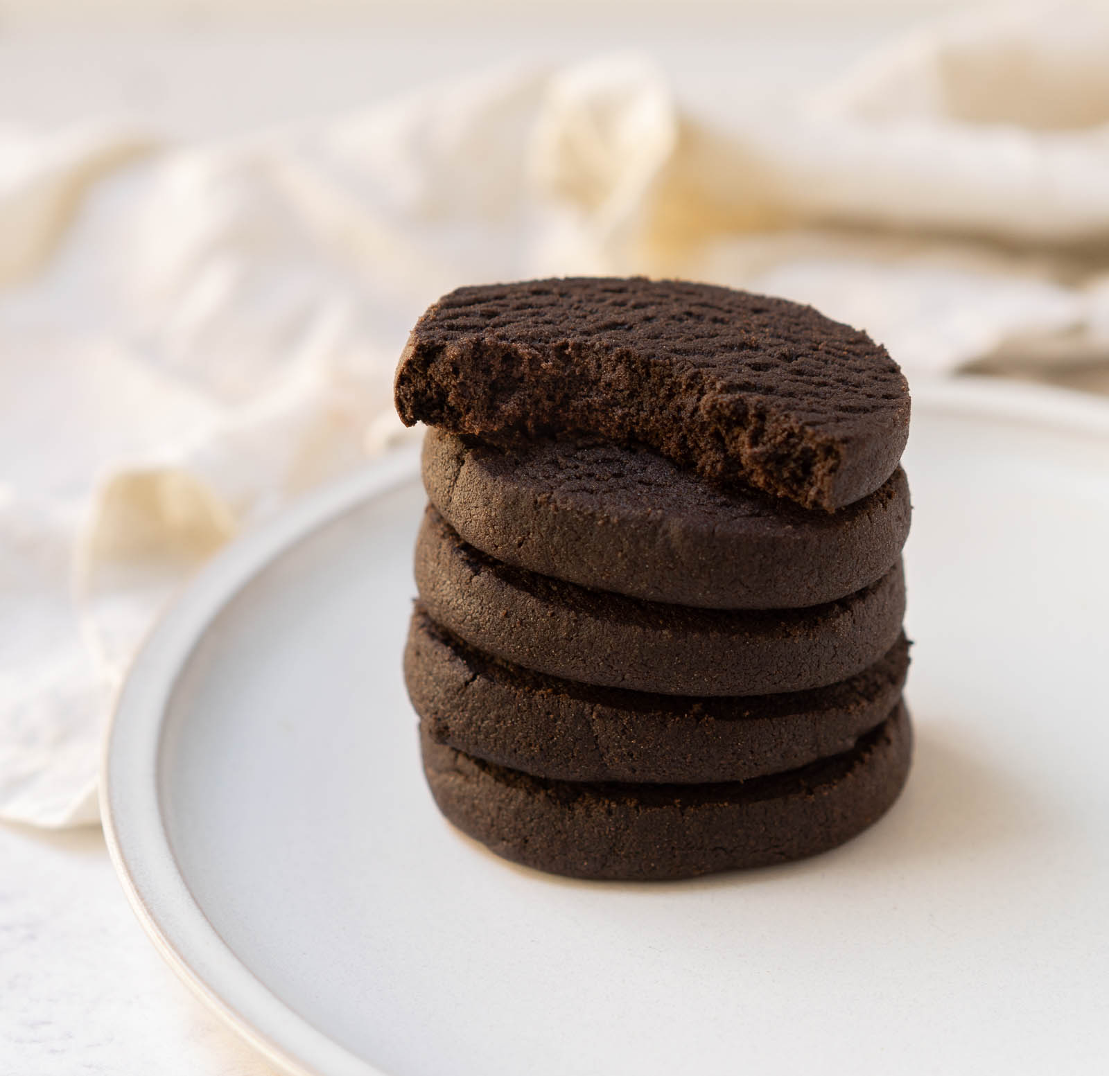 chocolate almond shortbread cookies stacked on a plate.