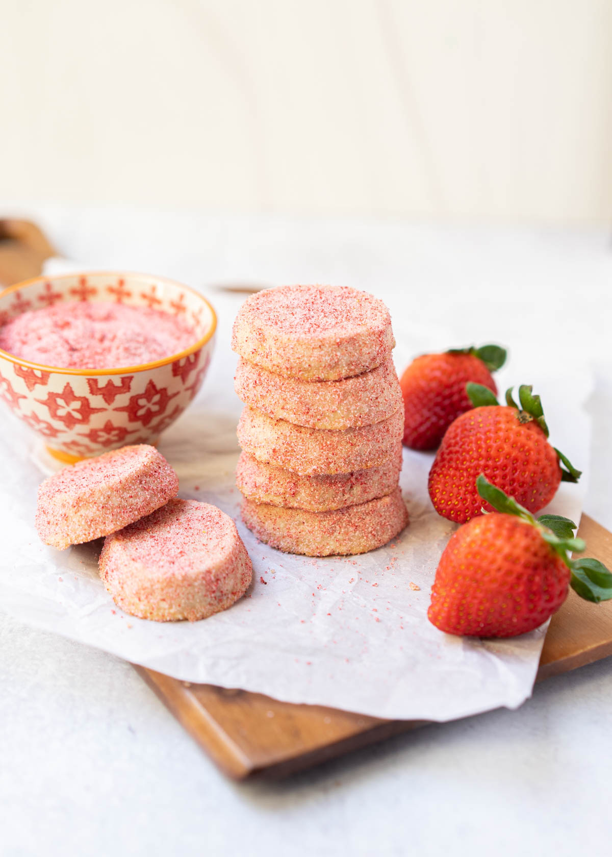 strawberry shortbread cookies stacked on cutting board.