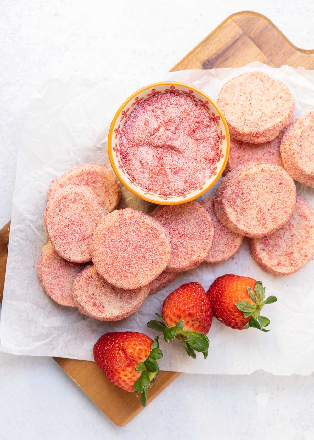 strawberry shortbread cookies laid on cutting board with strawberry sugar.