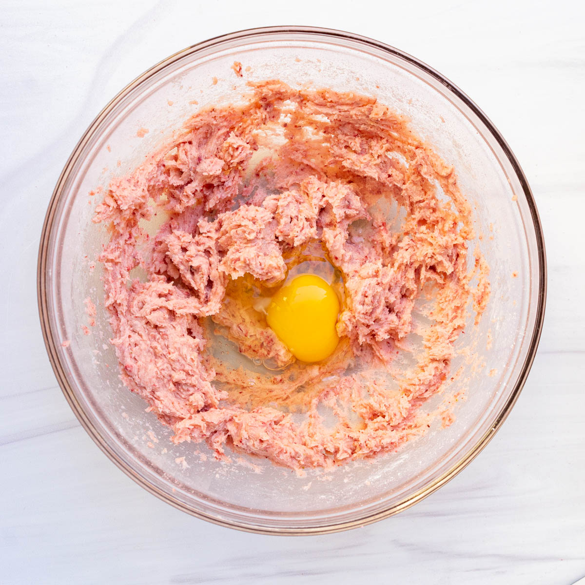 strawberry sugar cookies with egg in mixing bowl.