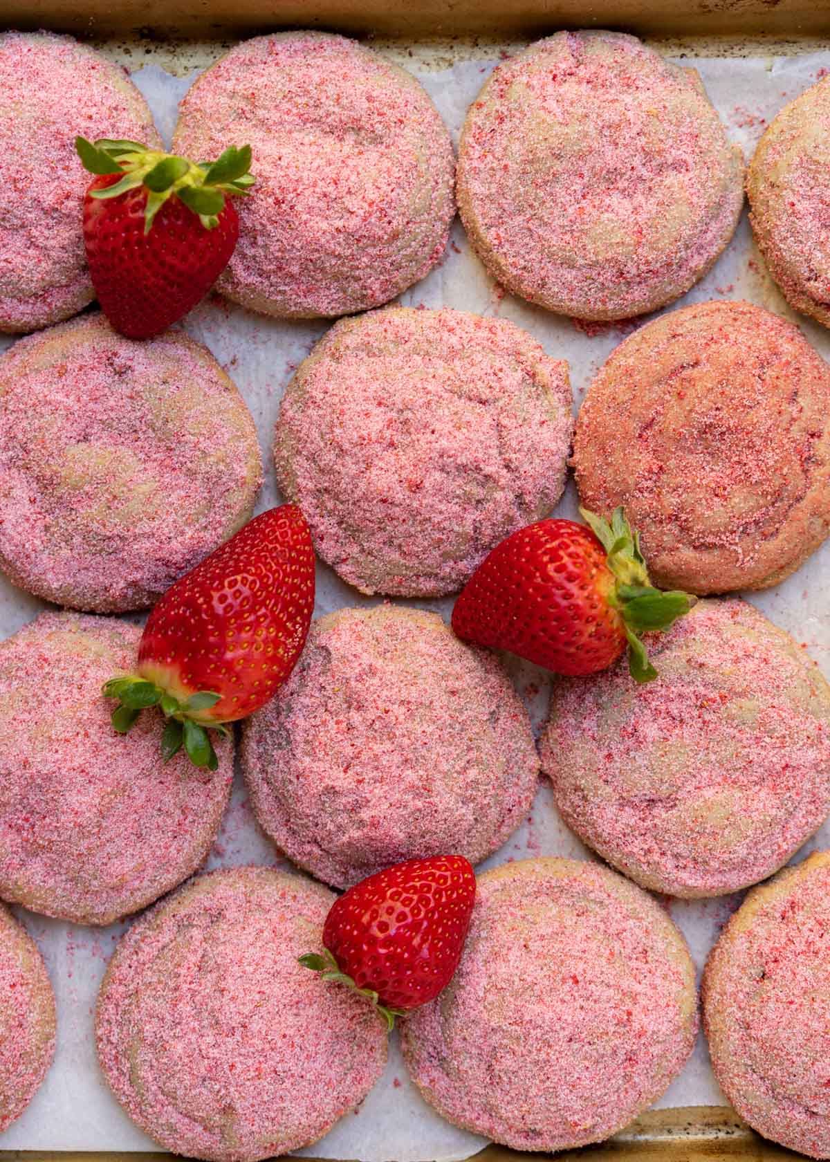 strawberry sugar cookies on baking sheet with fresh strawberries.