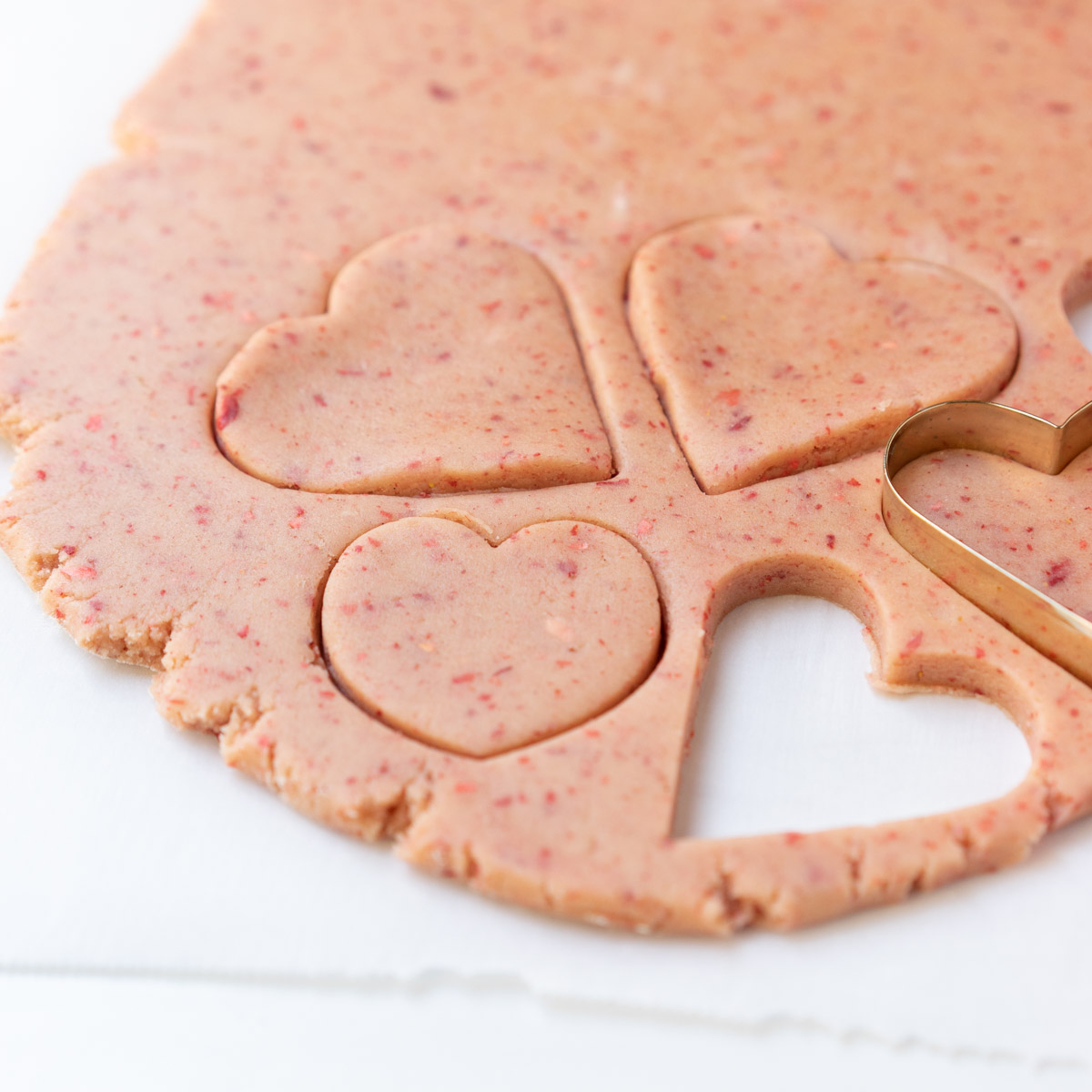 Strawberry Cut-Out Sugar Cookies dough with heart shaped cut outs.