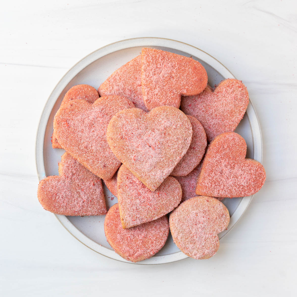 strawberry cut-out sugar cookies stacked on a plate.