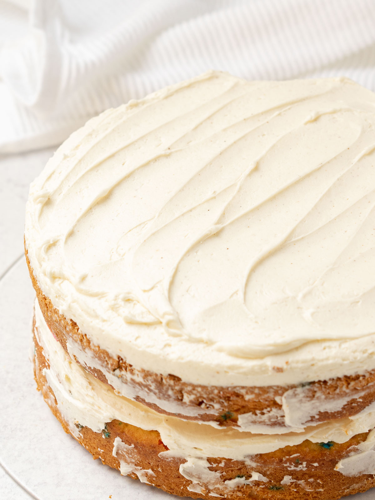 Vanilla American buttercream frosting spread on two layer cake.