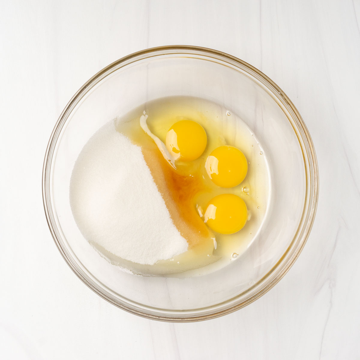 Eggs, sugar and vanilla in bowl before mixing.