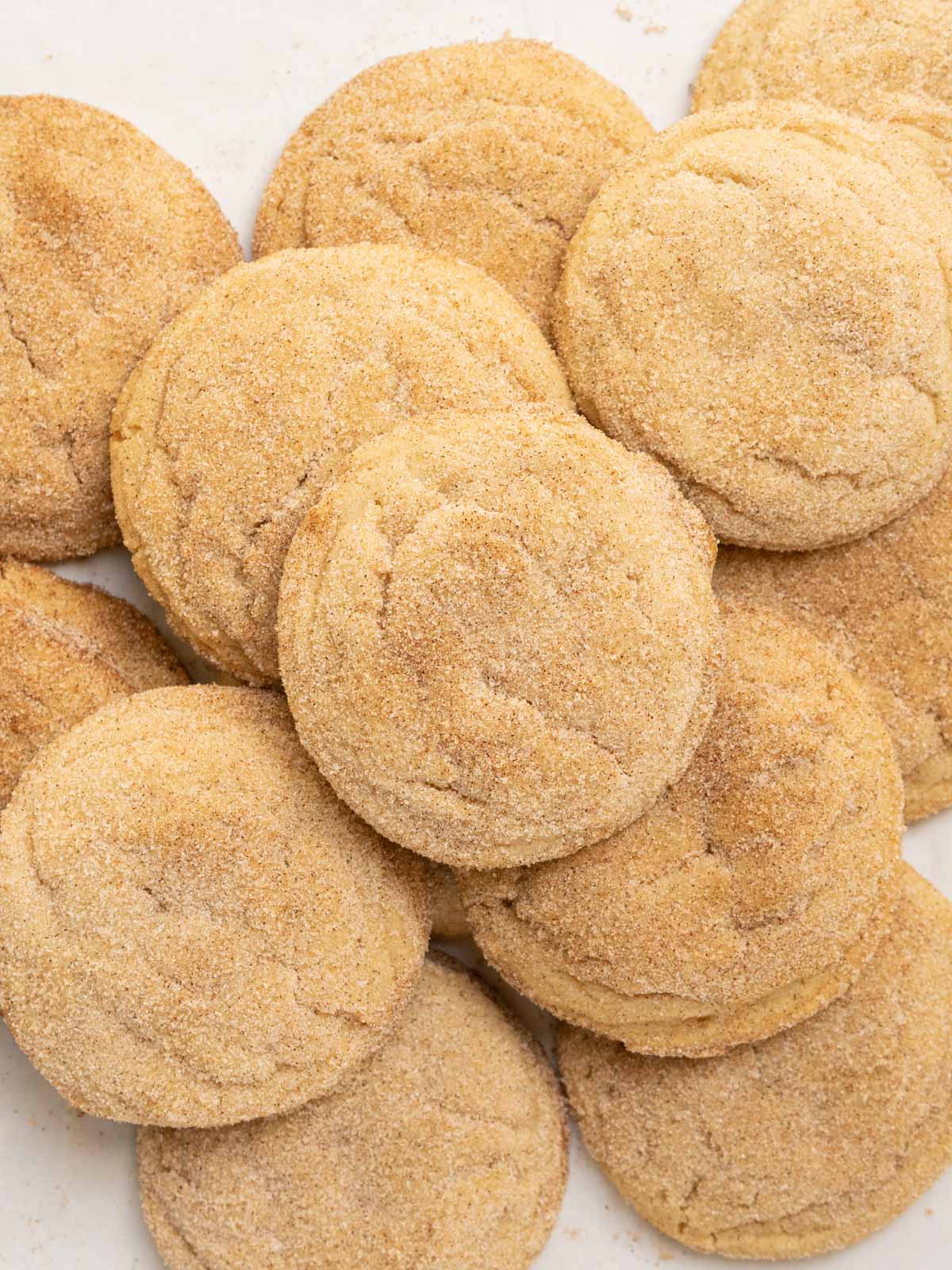 Mexican cinnamon cookies stacked on baking pan.