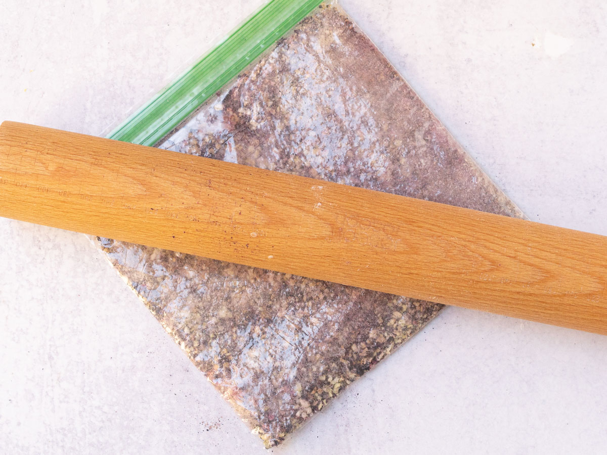 crushing freeze dried blueberries in bag with rolling pin.